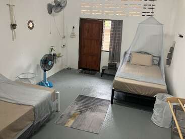 Se trata de una habitación sencilla y limpia con dos camas individuales, mosquitera, dos ventiladores, decoración de pared, una alfombra y mobiliario mínimo para mayor comodidad.