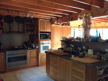 La imagen muestra una cocina cálida y acogedora, con armarios de madera, horno de acero inoxidable e isla central, bañada por la luz natural de la ventana.