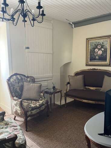 Cette pièce chaleureuse est agrémentée de fauteuils vintage, d'une causeuse assortie, d'une table basse rustique, d'un tableau floral, de murs aux tons neutres, d'un tapis tissé et d'un lustre noir.