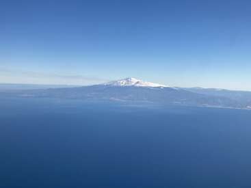 L'image représente un paysage serein composé d'une montagne enneigée, d'une vaste étendue d'eau et d'un ciel bleu clair, évoquant un sentiment de tranquillité et de beauté naturelle.