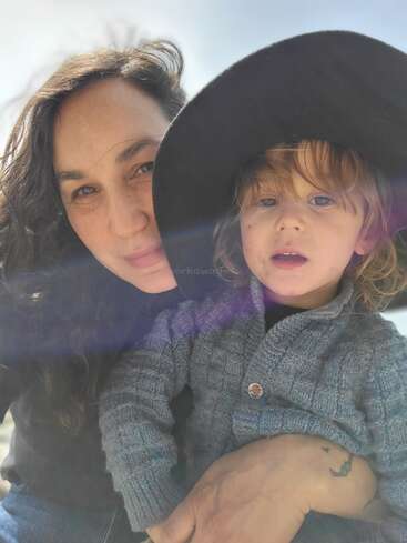 The image shows a woman and a child posing for a selfie, with the woman on the left and the child on the right, both wearing hats.