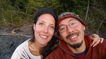 L'image montre une photographie de deux personnes, probablement un homme et une femme, se tenant ensemble, l'homme à gauche et la femme à droite, posant pour une photo.