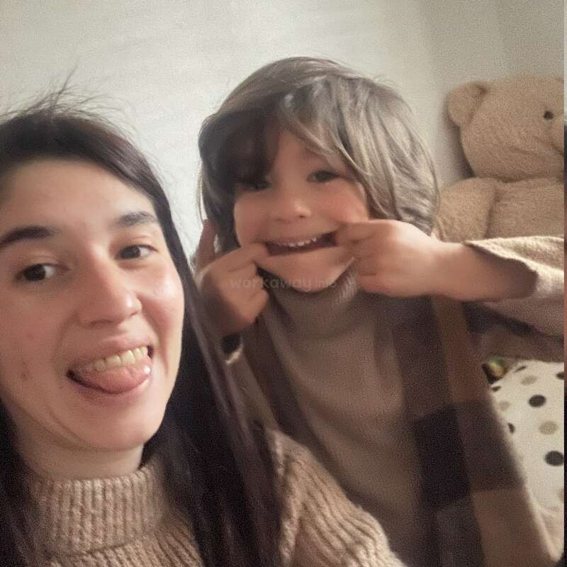 A woman and a child pose for a playful selfie. The woman sticks out her tongue, while the child makes a funny face, both smiling warmly.