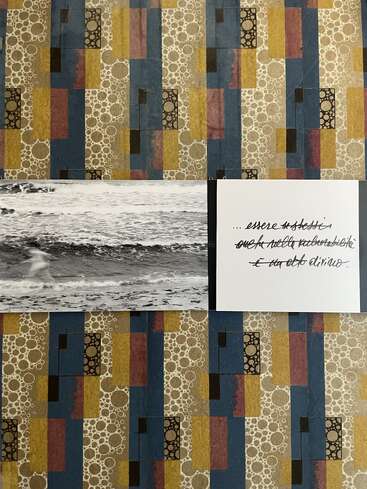 A patterned background frames a black-and-white photo of waves and a blurred figure. Beside it, handwritten Italian text is displayed on a white card.