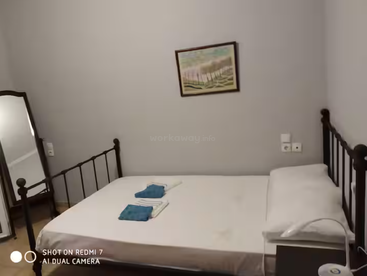 Dieses gemütliche Schlafzimmer verfügt über ein Doppelbett mit weißer Bettwäsche, zwei blaue Handtücher, einen Nachttisch, ein Wandbild und einen Standspiegel in der Ecke.
