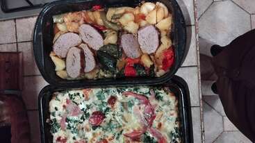 Esta imagem mostra duas bandejas retangulares de comida caseira, uma com bolo de carne fatiado e legumes assados, a outra com um prato cremoso assado coberto com ervas.