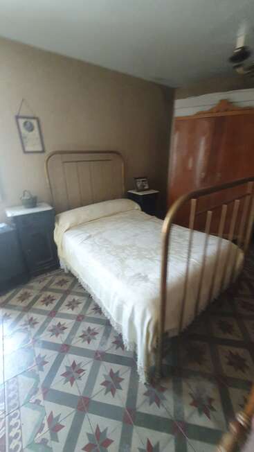 Cette image montre une chambre à coucher de style rétro, avec un lit à structure métallique, un sol en carrelage à motifs, une armoire en bois, des tables de chevet, un tableau encadré et des murs aux tons neutres, qui respirent la simplicité.