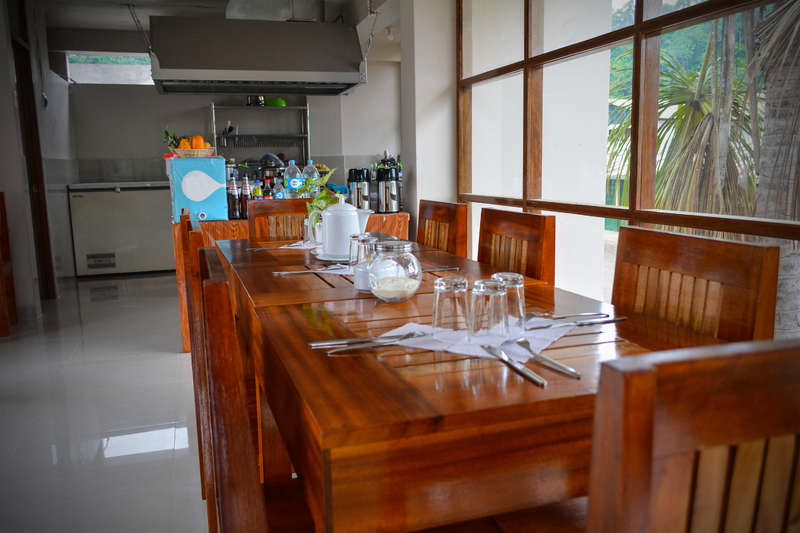 La imagen muestra un comedor con mesa y sillas, un gran ventanal y una chimenea, que crean un ambiente cálido y acogedor para una reunión familiar o un acto social.
