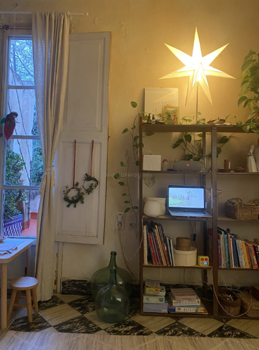 Chambre confortable avec fenêtre ouverte, plantes, lampe étoilée allumée, étagères remplies de livres, ordinateur portable diffusant des animations, paniers en osier, couronnes décoratives et bouteilles en verre.