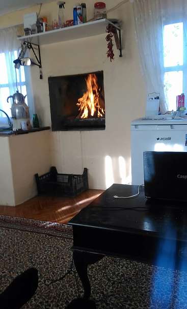 L'image représente une pièce confortable avec une cheminée, une petite table et un réfrigérateur, dans une atmosphère chaleureuse et accueillante.