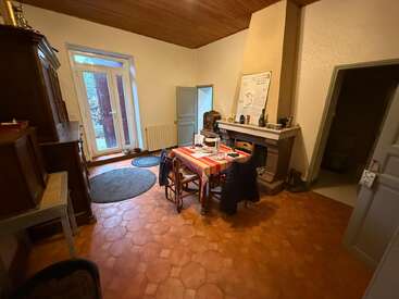 Dieser gemütliche Raum ist mit Terrakottafliesen, einer Holzdecke, einem Kamin, runden Teppichen und einem Holztisch mit Stühlen ausgestattet. Es gibt natürliches Licht und eine rustikale Einrichtung.