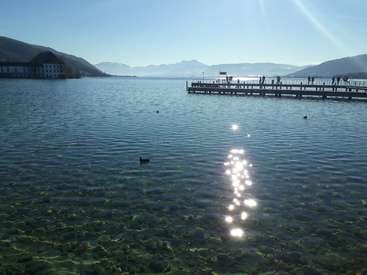 The image depicts a serene lake scene with a dock, mountains in the background, and a clear blue sky, evoking a sense of tranquility and natural beauty.