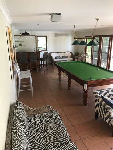 Das Bild zeigt einen geräumigen Raum mit einem Billardtisch, einer Bar und einem Sitzbereich, der mit seinen Erdtönen und dem natürlichen Licht eine warme und einladende Atmosphäre ausstrahlt.