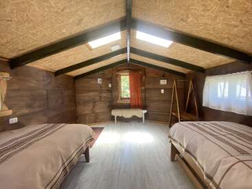 Dieses gemütliche Holzhüttenzimmer verfügt über zwei Betten, eine Holzbank, natürliches Licht durch Oberlichter und Fenster, eine rustikale Einrichtung, eine Holzbalkendecke und eine minimalistische, einladende Atmosphäre.