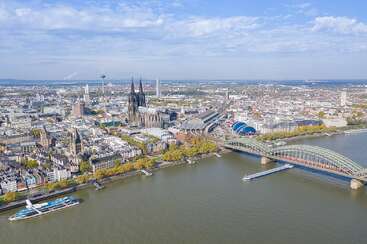 The image depicts a cityscape with a river, featuring a bridge and buildings, likely showcasing a European city, with a prominent building in the background and a bridge spanning the waterway.