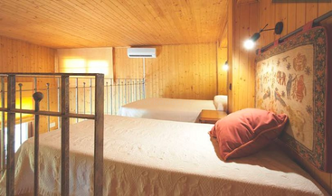 The image depicts a room with a bed and a table, featuring a large window and a door, with a white wall and a gray floor, conveying a sense of simplicity and minimalism.