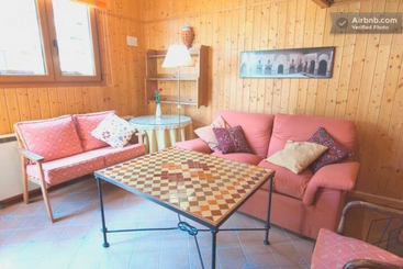 The image depicts a cozy living room with a wooden table and chairs, a fireplace, and a bookshelf, exuding warmth and comfort, evoking a sense of a peaceful and inviting space.