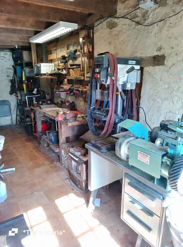 Esta imagem mostra uma oficina com várias ferramentas de marcenaria, maquinário, bancadas e equipamentos. O espaço é organizado, mas movimentado, com ferramentas e materiais por toda parte.