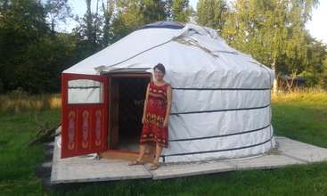 A imagem mostra uma yurt, provavelmente uma residência tradicional, com um telhado inclinado e uma pequena janela, em um cenário natural, evocando uma sensação de simplicidade e funcionalidade.