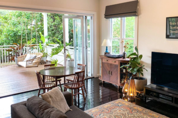 The image depicts a living room with a large window, a table, and a bookshelf, showcasing a modern and stylish interior design. The room is well-lit and has a neutral color scheme.