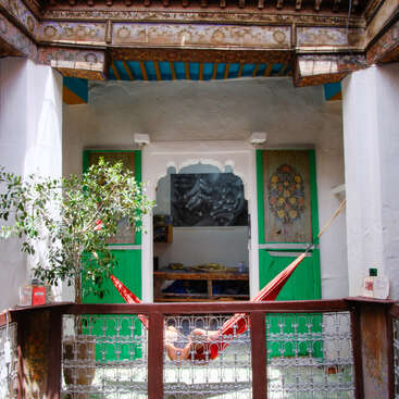L'image représente une cour sereine avec un hamac, un arbre en pot et une table, mettant en valeur un mélange harmonieux d'éléments naturels et d'architecture décorative.