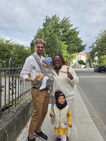 Uma família feliz de quatro pessoas está ao ar livre, tomando sorvete juntos. Eles estão vestidos com roupas quentes, sorrindo e parecem estar em um passeio tranquilo em um bairro.