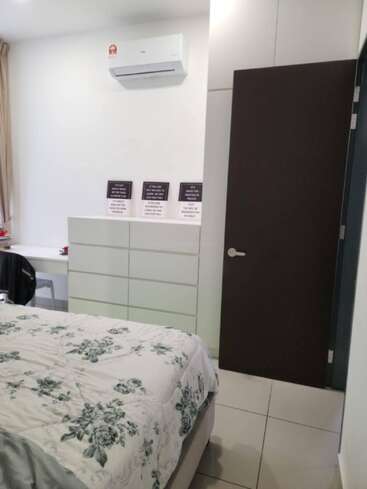 Une chambre bien rangée avec un couvre-lit à fleurs, une commode blanche, un climatiseur et une porte ouverte. Trois affiches motivantes sont accrochées au-dessus de la commode.