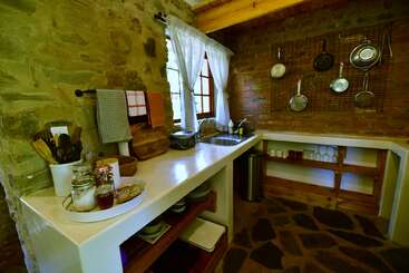 L'image représente une cuisine avec une table et des chaises, dotée d'une grande fenêtre, d'une cheminée et d'un coin repas, l'accent étant mis sur la table et les chaises. La pièce est bien éclairée et dégage une atmosphère chaleureuse.