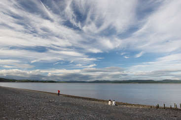 The image depicts a serene scene of a body of water with a shoreline, featuring a few trees and a clear sky, evoking a sense of tranquility and natural beauty.