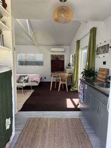 Dieses gemütliche Studio verfügt über eine kompakte Küche, einen Esstisch und ein Bett. Natürliches Licht, grüne Vorhänge und eine minimalistische Einrichtung schaffen einen hellen, einladenden und funktionalen Raum.