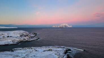 Eine friedliche Winterlandschaft mit schneebedeckten Ufern, ruhigem, dunklem Wasser und einer verschneiten Insel in der Ferne unter einem atemberaubenden rosa-blauen Abendhimmel strahlt eine ruhige Schönheit aus.