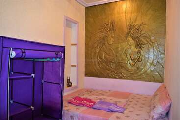 Esse quarto aconchegante tem um guarda-roupa roxo, uma cama com lençóis estampados e um mural dourado incrível na parede, mostrando duas figuras com cabelos esvoaçantes.