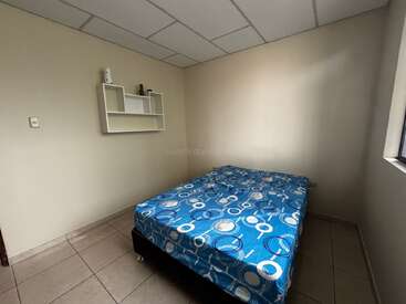 Cette photo montre une petite chambre simple avec un lit à motifs bleus, des étagères blanches fixées au mur, des murs de couleur crème, un sol carrelé et une fenêtre.