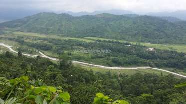 The image depicts a serene landscape featuring a winding road, lush greenery, and a mountainous backdrop, with a subtle watermark in the center.