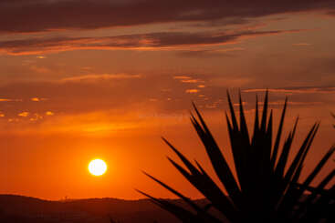 L'image représente une scène sereine d'un coucher de soleil, avec un grand soleil dans le ciel, jetant une lueur chaude sur un paysage tranquille, évoquant des sentiments de paix et de relaxation.