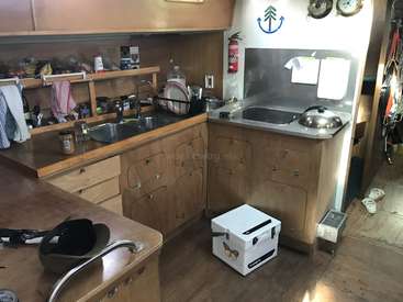 Das Bild zeigt eine kompakte Küche mit Holzschränken und Arbeitsplatten, die mit einer Spüle, einem Herd und einem Kühlschrank ausgestattet ist und einen gemütlichen und funktionalen Kochbereich darstellt.