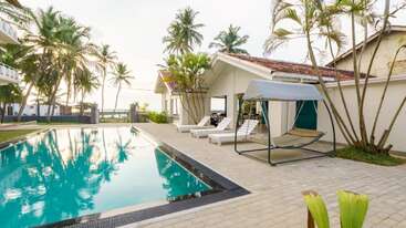 La imagen representa un entorno sereno al aire libre, con una piscina, palmeras y una casa, que evoca una sensación de relajación y tranquilidad. El ambiente es apacible e idílico.