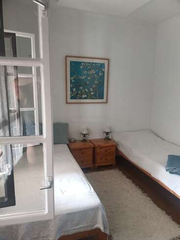 Esta acogedora habitación cuenta con dos camas individuales con ropa de cama pálida, mesillas de noche de madera, lámparas clásicas, una suave alfombra blanca y un cuadro floral en la pared.