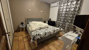 L'image représente une chambre composée d'un lit, d'un bureau et d'une chaise, avec une dominante de blanc et des touches de vert et de marron, évoquant un sentiment de simplicité et de minimalisme.