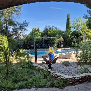La imagen representa un oasis de serenidad en el patio trasero, con piscina, exuberante vegetación y un patio, que evoca una sensación de relajación y tranquilidad.