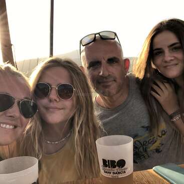The image shows four people posing for a photo, with two women on the left and two on the right, all wearing casual clothing and smiling at the camera.