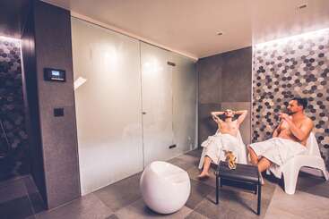 La imagen representa una serena escena de dos individuos relajándose en un balneario, rodeados de un ambiente tranquilo, centrado en su ocio y relajación. La escena transmite una sensación de calma y serenidad.