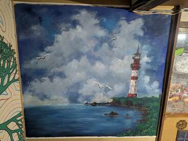Cette peinture représente un paysage marin avec un phare rouge et blanc sur une côte rocheuse, entouré d'une végétation luxuriante, de nuages spectaculaires et de plusieurs mouettes volant au-dessus.