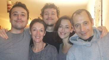 The image shows a group of people posing for a photo, with a mix of men and women, all dressed in casual attire, likely taken during a family gathering or social event.