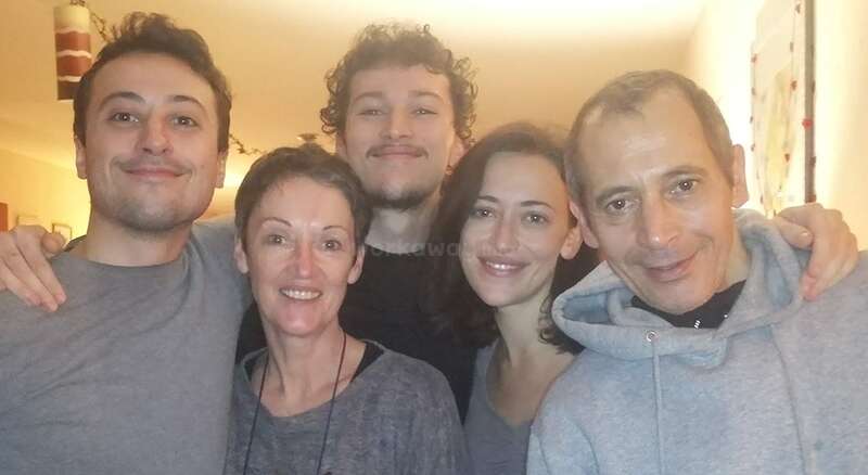 The image shows a group of people posing for a photo, with a mix of men and women, all dressed in casual attire, likely taken during a family gathering or social event.