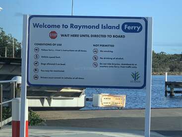 Uma placa dá as boas-vindas aos passageiros na balsa de Raymond Island, informando as condições de uso e as proibições, como proibição de fumar, proibição de álcool, regras para veículos e orientações sobre animais de estimação.