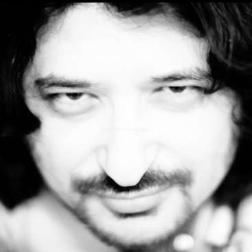 The image is a black-and-white close-up photograph of a man\'s face, with a blurred background and a watermark in the center.