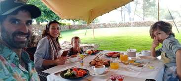 Das Bild zeigt eine Familie, die gemeinsam eine Mahlzeit genießt, mit einem Tisch voller Speisen und Getränke, die ein Gefühl der Zusammengehörigkeit und des Feierns vermitteln. Die Atmosphäre ist warm und einladend.