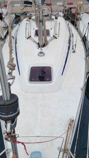 This image shows the deck of a docked sailboat, with rigging, ropes, and hatches visible on the clean white surface, ready for sailing.