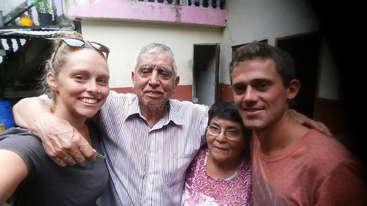 A imagem mostra um grupo de pessoas posando para uma foto, com uma mistura de adultos e crianças, todos vestidos com roupas casuais, em um plano de fundo neutro.